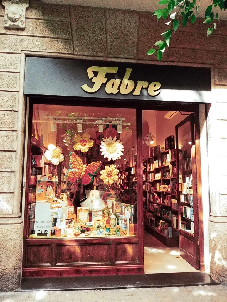 Block - Left - 13 of 16 - Petsolt Family Storefront of a bookstore named Fabre, with a glass window displaying books and colorful paper flowers.