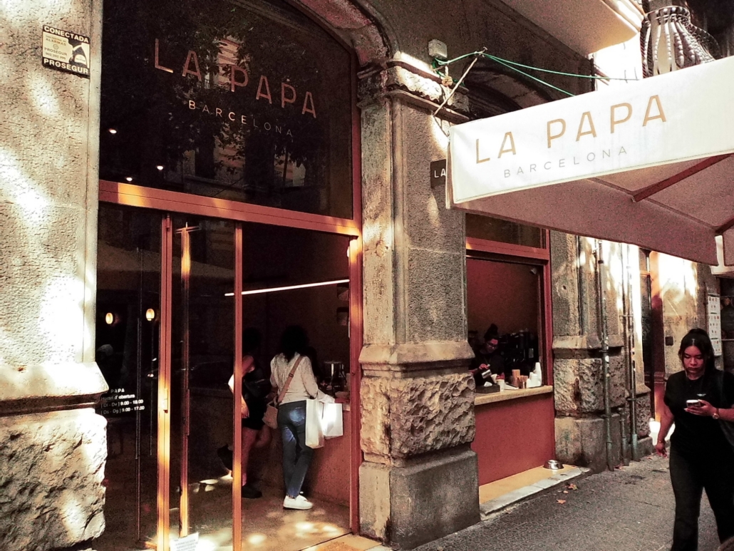 Block - Left - 16 of 16 - Petsolt Family Exterior view of La Papa Barcelona restaurant with stone columns, glass doors, and a white awning showing the name.