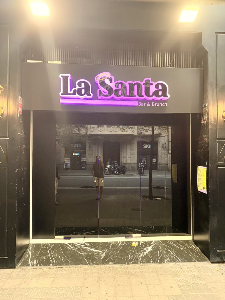 Block - Mountian - 1 of 13 - Petsolt Family Neon sign reading 'La Santa Bar & Brunch' above a glass storefront entrance; a person stands in the doorway.