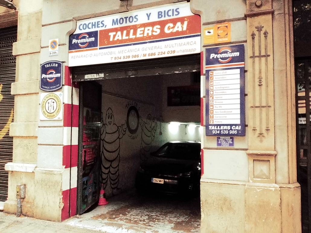 Block - Mountian - 4 of 13 - Petsolt Family Automotive repair shop entrance with signs reading 'Tallers CAI' and 'Premium,' and a car visible inside under a shutter.