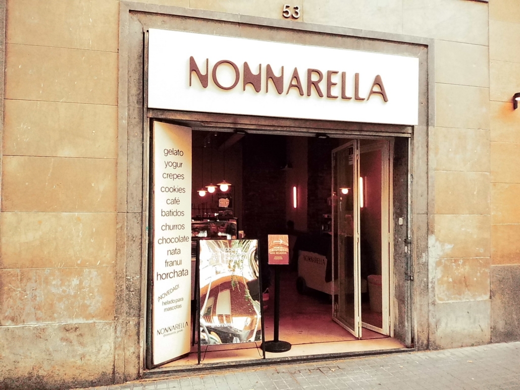 Block - Right - 2 of 4 - Petsolt Family Storefront entrance with a white sign reading 'NONNARELLA' above the doorway; open doors reveal a cafe interior with a vertical menu board listing treats like gelato, yogurt, crepes, cookies, chocolate, nata, churros, horchata.