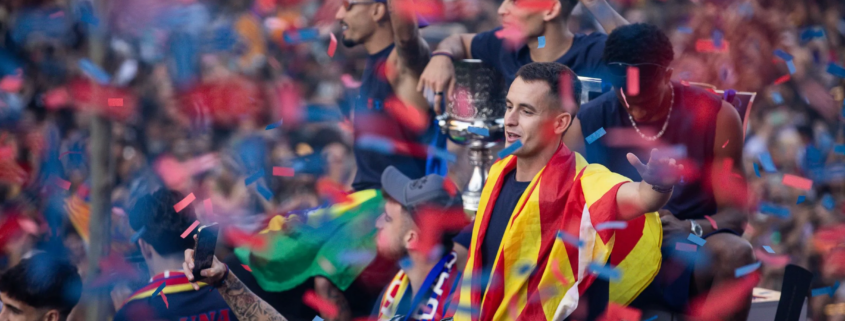 Crowd of celebrateers in Spain flag colors, confetti falling during a victory parade.