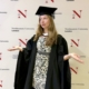 2026-07- London Ireland - 1 of 23 - Petsolt Family Graduate in cap and gown gesturing with hands in front of a Northeastern University London backdrop.