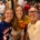 Three friends take a selfie in a crowded street crowd, all smiling and wearing colorful sports jerseys.