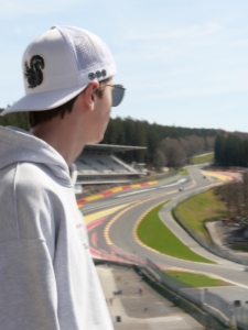 Spa-Francorchamps Person in a white mesh-back cap and sunglasses looks over a winding racetrack from a high vantage point.